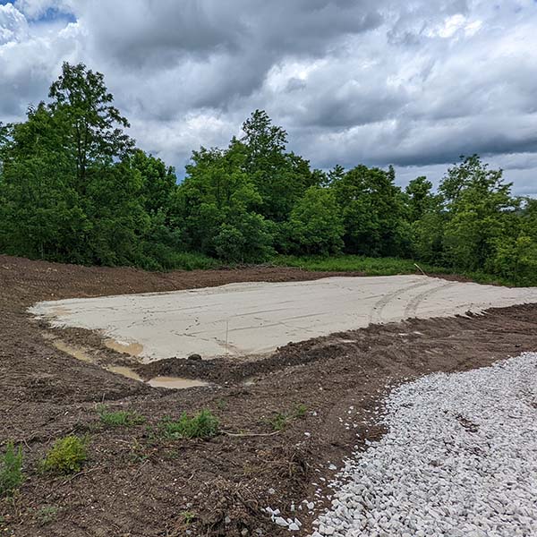 Cleared, leveled, and graveled pad for barn construction.