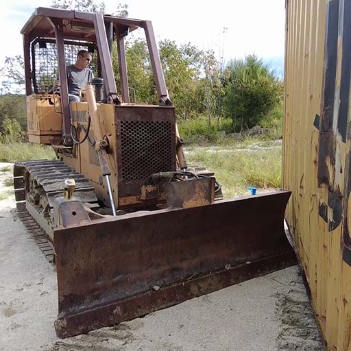 Bulldozer positioning a shipping container.
